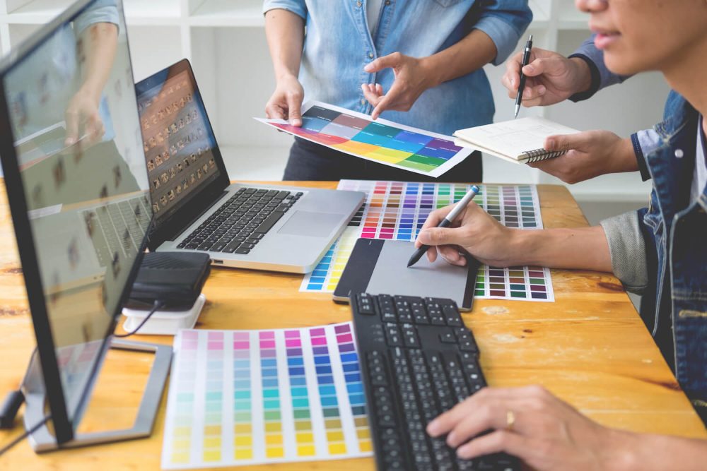 graphic-designer-team-working-web-design-using-color-swatches-editing-artwork-using-tablet-stylus-desks-busy-creative-office (1)